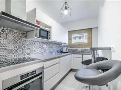 a white kitchen with a stool in the middle of it at Majestic in Cannes