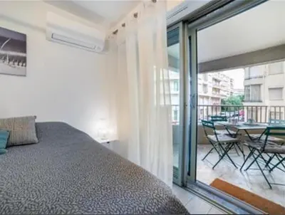 a bedroom with a bed and a balcony with a table at Majestic in Cannes