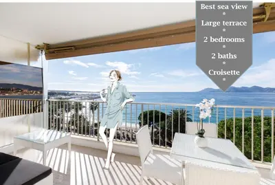 a woman standing on a balcony with a view of the ocean at On La Croisette deluxe 2 bedrooms 2 baths in Cannes