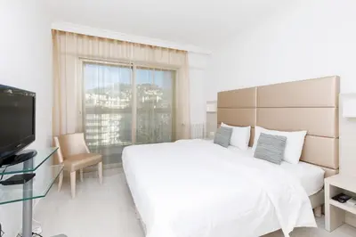 a white bedroom with a large bed and a tv at On La Croisette deluxe 2 bedrooms 2 baths in Cannes