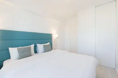 a bedroom with a large white bed with a blue headboard at On La Croisette deluxe 2 bedrooms 2 baths in Cannes