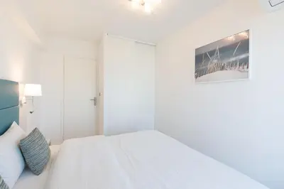 a white bedroom with a bed and a picture on the wall at On La Croisette deluxe 2 bedrooms 2 baths in Cannes