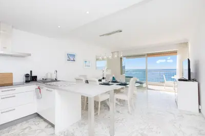 a white kitchen with a dining table and a view of the ocean at On La Croisette deluxe 2 bedrooms 2 baths in Cannes
