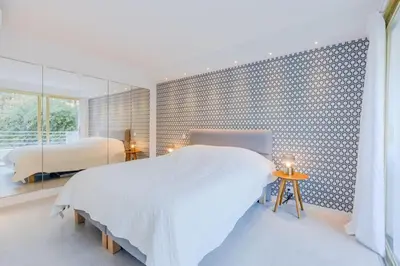 a white bedroom with a bed and a mirror at 4-Room Apartment of 96m with a Stunning View in Cannes