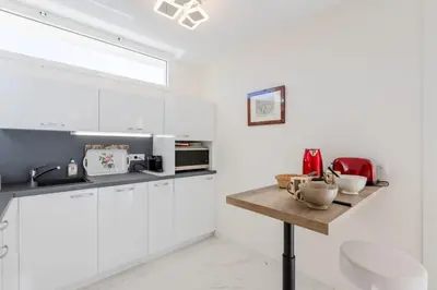 a kitchen with white cabinets and a wooden table at Luxurious 2-room Apartment in Palm Beach in Cannes