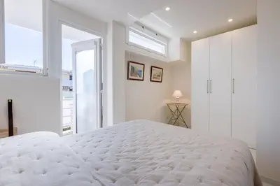 a white bedroom with a large bed and a window at Luxurious 2-room Apartment in Palm Beach in Cannes