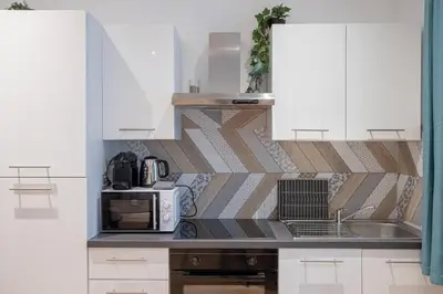 a kitchen with white cabinets and a microwave at Le Sweet Forville 2 - Palais des Festivals - Marché provençal - Plage - Clim - Au calme in Cannes