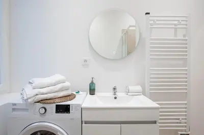 a white bathroom with a washing machine and a mirror at Le Sweet Forville 2 - Palais des Festivals - Marché provençal - Plage - Clim - Au calme in Cannes