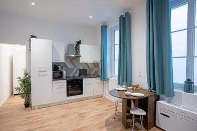 a kitchen with white cabinets and a wooden table with chairs at Le Sweet Forville 2 - Palais des Festivals - Marché provençal - Plage - Clim - Au calme in Cannes