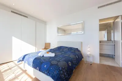 a white bedroom with a bed and a mirror at Appartement 3 chambres 125 m2 avec vue exceptionnelle face à la mer in Cannes