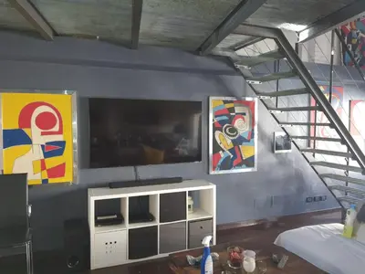 a living room with a tv and paintings on the wall at Le Port Luxury Loft Duplex in Cannes