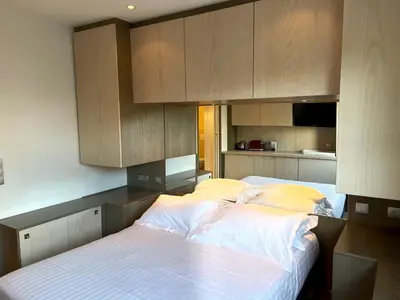 a bedroom with a bed with white sheets and wooden cabinets at Chambre idéalement située à 50m de la Croisette in Cannes
