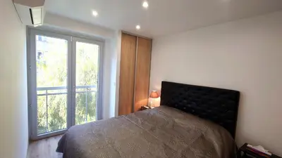 a bedroom with a bed and a large window at Magnifique appartement à 10mn du Palais in Cannes