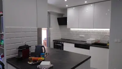 a kitchen with white cabinets and a black counter top at Magnifique appartement à 10mn du Palais in Cannes