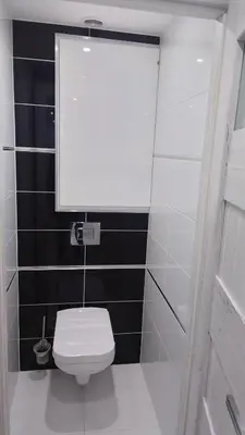 a white toilet in a bathroom with black tiles at Magnifique appartement à 10mn du Palais in Cannes