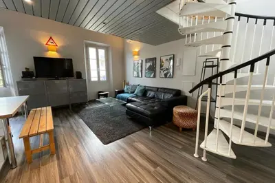 a living room with a black leather couch and a spiral staircase at Riouffe 2 bedroom duplex apartment in the center of Cannes in Cannes