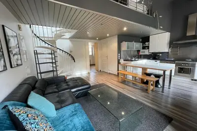 a living room with a black couch and a kitchen at Riouffe 2 bedroom duplex apartment in the center of Cannes in Cannes