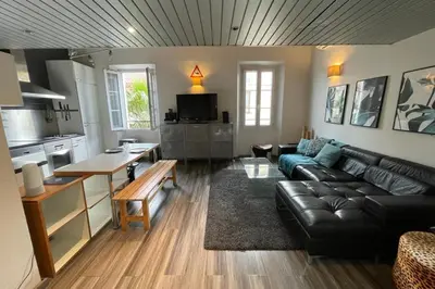 a living room with a black leather couch and a kitchen at Riouffe 2 bedroom duplex apartment in the center of Cannes in Cannes