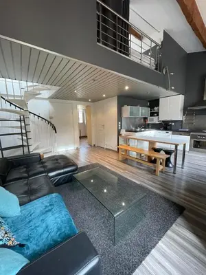 a living room with a black couch and a kitchen at Riouffe 2 bedroom duplex apartment in the center of Cannes in Cannes
