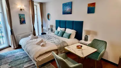 a bedroom with a large bed and a table and chairs at LB Vacation Rentals I Deluxe Studio w Balcony - 5mn Center I Casa d'Azur in Cannes
