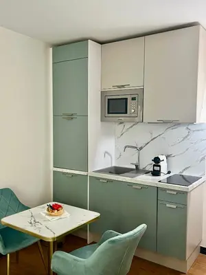 a kitchen with blue chairs and a table and a microwave at LB Vacation Rentals I Deluxe Studio w Balcony - 5mn Center I Casa d'Azur in Cannes