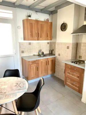 a kitchen with wooden cabinets and a sink and a table at APPARTEMENT WOOD DESING PROCHE CANNES in Le Cannet