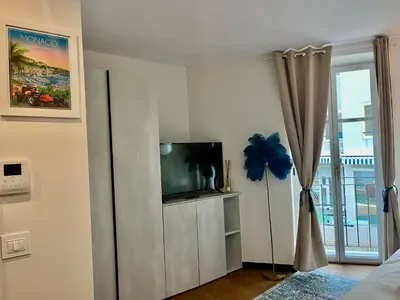 a living room with a tv and a curtain at LB Vacation Rentals I Large Superieure Room with Balcony I Casa d'Azur in Cannes