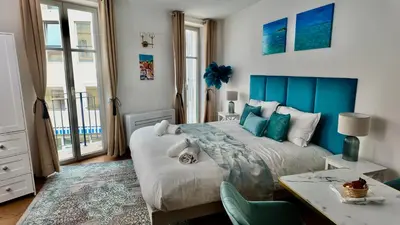 a bedroom with a bed with a blue headboard and a desk at LB Vacation Rentals I Large Superieure Room with Balcony I Casa d'Azur in Cannes