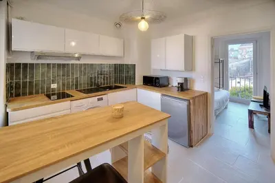 a kitchen with white cabinets and a wooden counter top at IMMOGROOM - Refurbished - Suquet - Sea view in Cannes