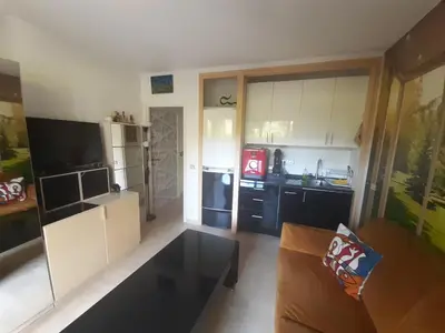 a kitchen with white cabinets and a couch in a room at IDEAL POUR COUPLE in Cannes