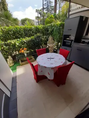 a patio with a table and four red chairs at IDEAL POUR COUPLE in Cannes