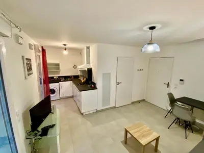 a living room with a table and a kitchen at PAUL DOUMER #1 By SCLS Locations in Le Cannet