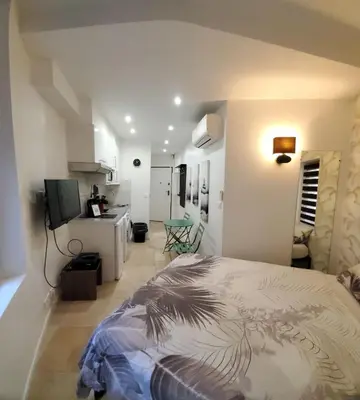 a bedroom with a bed and a room with a kitchen at STUDIO CENTRE CANNES FORVILLE in Cannes