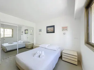 two beds in a room with white walls and mirrors at 2 bedroom apartment with parking 3 mins from La Croisette beach in Cannes