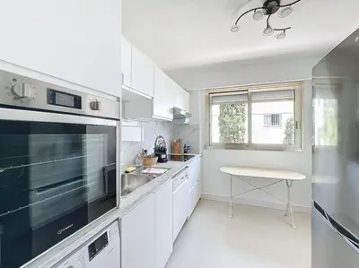 a kitchen with white cabinets and a sink and a window at 2 bedroom apartment with parking 3 mins from La Croisette beach in Cannes