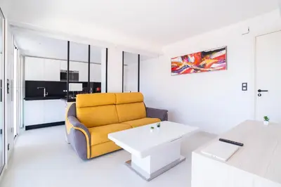 a living room with a yellow couch and a table at 1-Br Apartment Sea View Terrace & Parking in Cannes