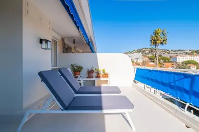 a balcony with blue chairs and a view of the city at 1-Br Apartment Sea View Terrace & Parking in Cannes