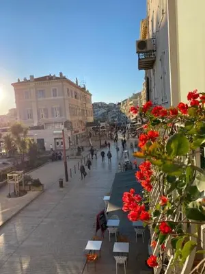 a city street with tables and chairs and red flowers at M.M.R. Au cœur de la vie cannoise in Cannes
