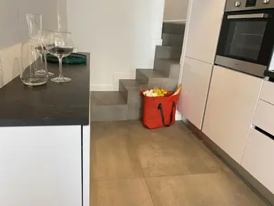 a kitchen with white cabinets and a staircase with wine glasses at M.M.R. Au cœur de la vie cannoise in Cannes
