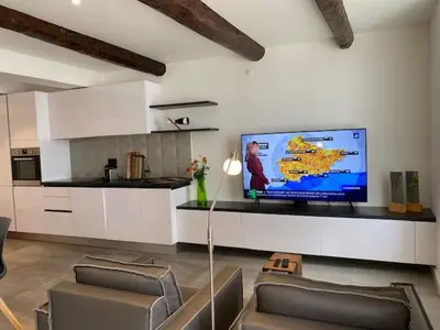 a living room with a flat screen tv and a kitchen at M.M.R. Au cœur de la vie cannoise in Cannes