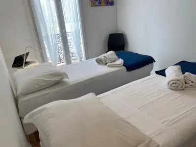 two twin beds in a room with a window at M.M.R. Au cœur de la vie cannoise in Cannes