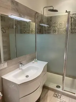 a white bathroom with a sink and a shower at M.M.R. Au cœur de la vie cannoise in Cannes