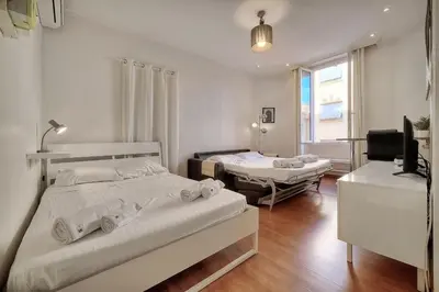 a bedroom with two beds and a television in it at IMMOGROOM - Cosy Studio - Forville market - AC in Cannes