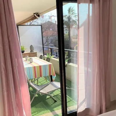 a room with a table and a balcony with a view at T2 proche de la gare, à 10 minutes à pieds de la Croisette, piscine & parking dans résidence de haut standing in Cannes