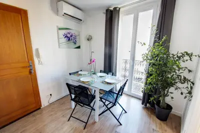 a dining room with a table and chairs and a plant at Lovely one bedroom apartment Gambetta Cannes in Cannes