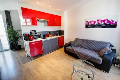 a living room with a couch and a kitchen with red cabinets at Lovely one bedroom apartment Gambetta Cannes in Cannes
