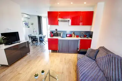 a living room with a couch and a kitchen with red cabinets at Lovely one bedroom apartment Gambetta Cannes in Cannes