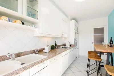 a white kitchen with a sink and a table at Elegance in Le Cannet