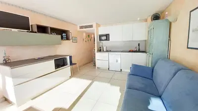 a living room with a blue couch and a kitchen at Les terrasses in Cannes