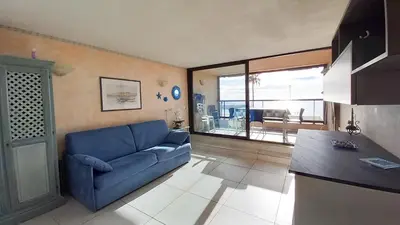 a living room with a blue couch and a kitchen at Les terrasses in Cannes